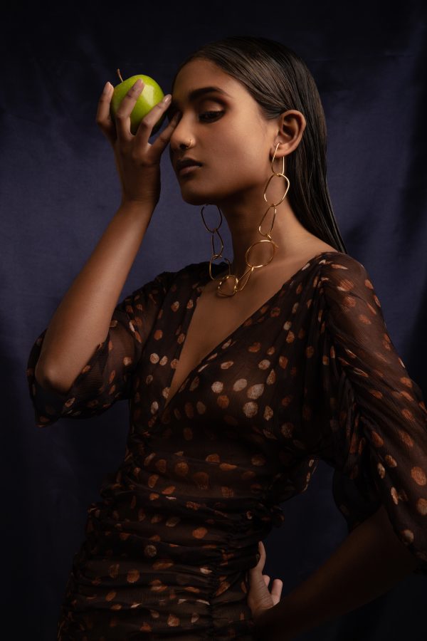 model wears eternal ear cuff made into a chain while holding an apple up to her face