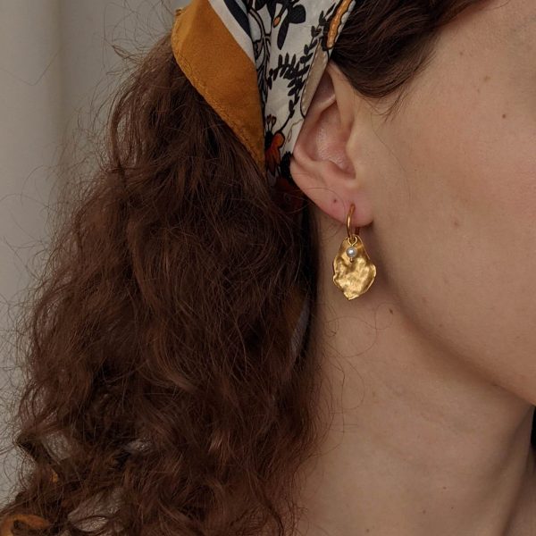 gold flourish earrings on ear